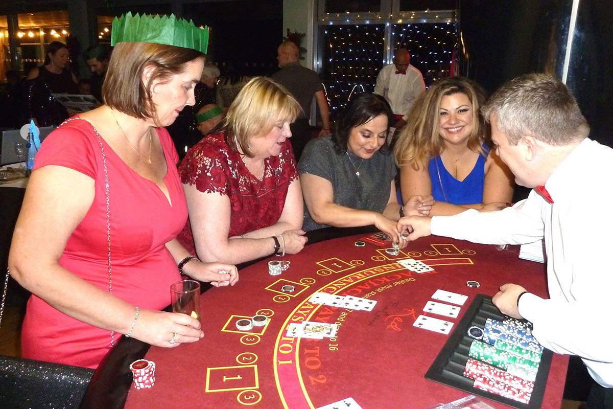 Smiling guests having fun playing blackjack at a Christmas casino party